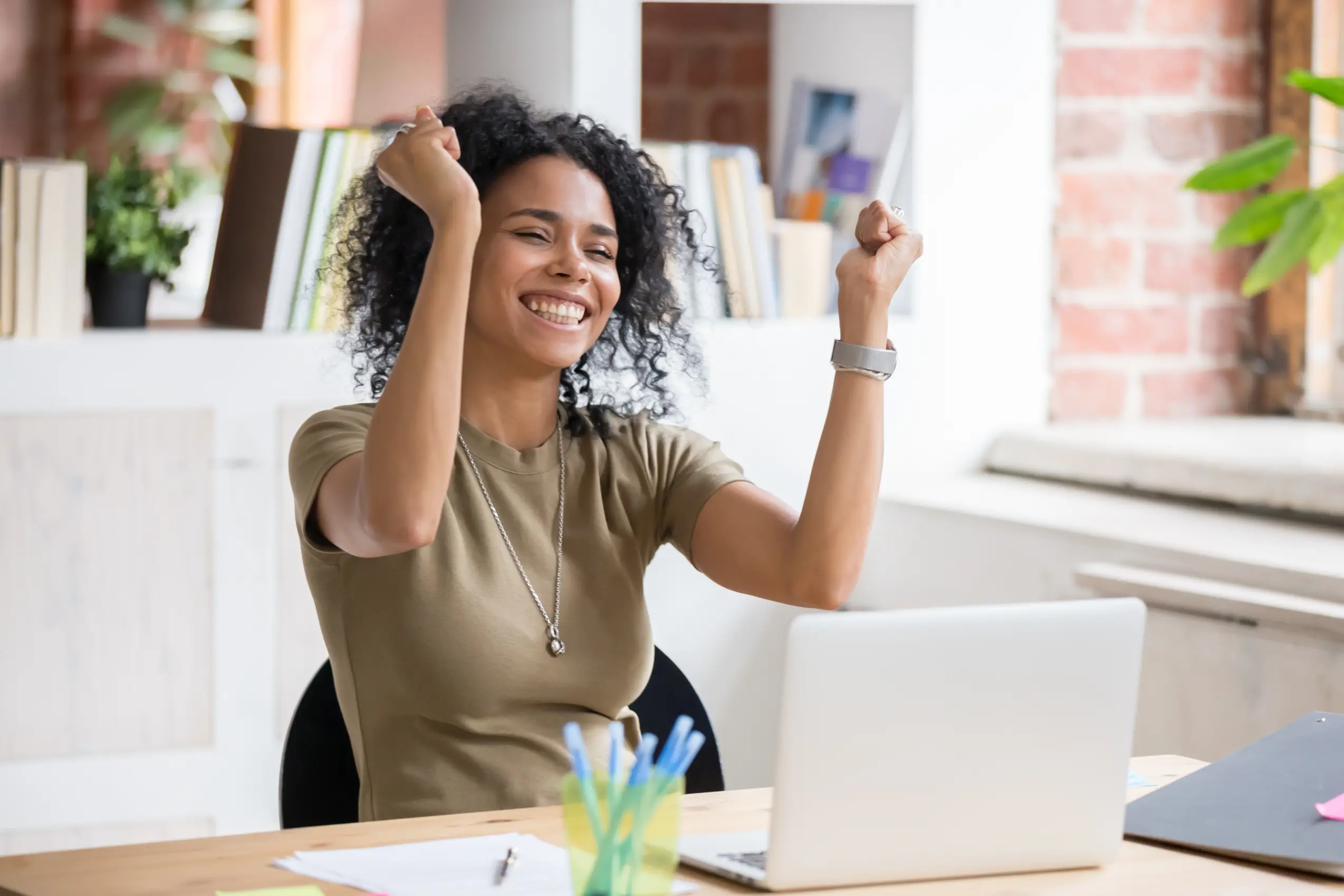 Business owner celebrating success at her laptop after securing effective risk management strategies