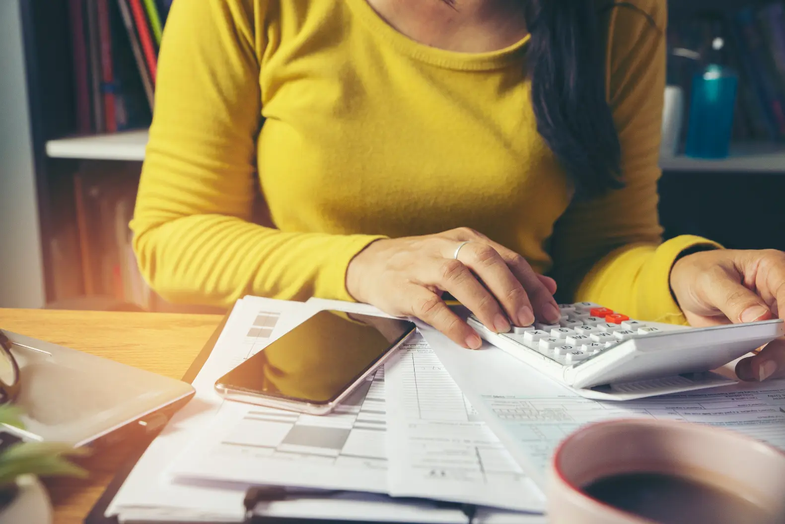 Professional using a calculator and reviewing documents while working on integrated tax advisory and financial planning