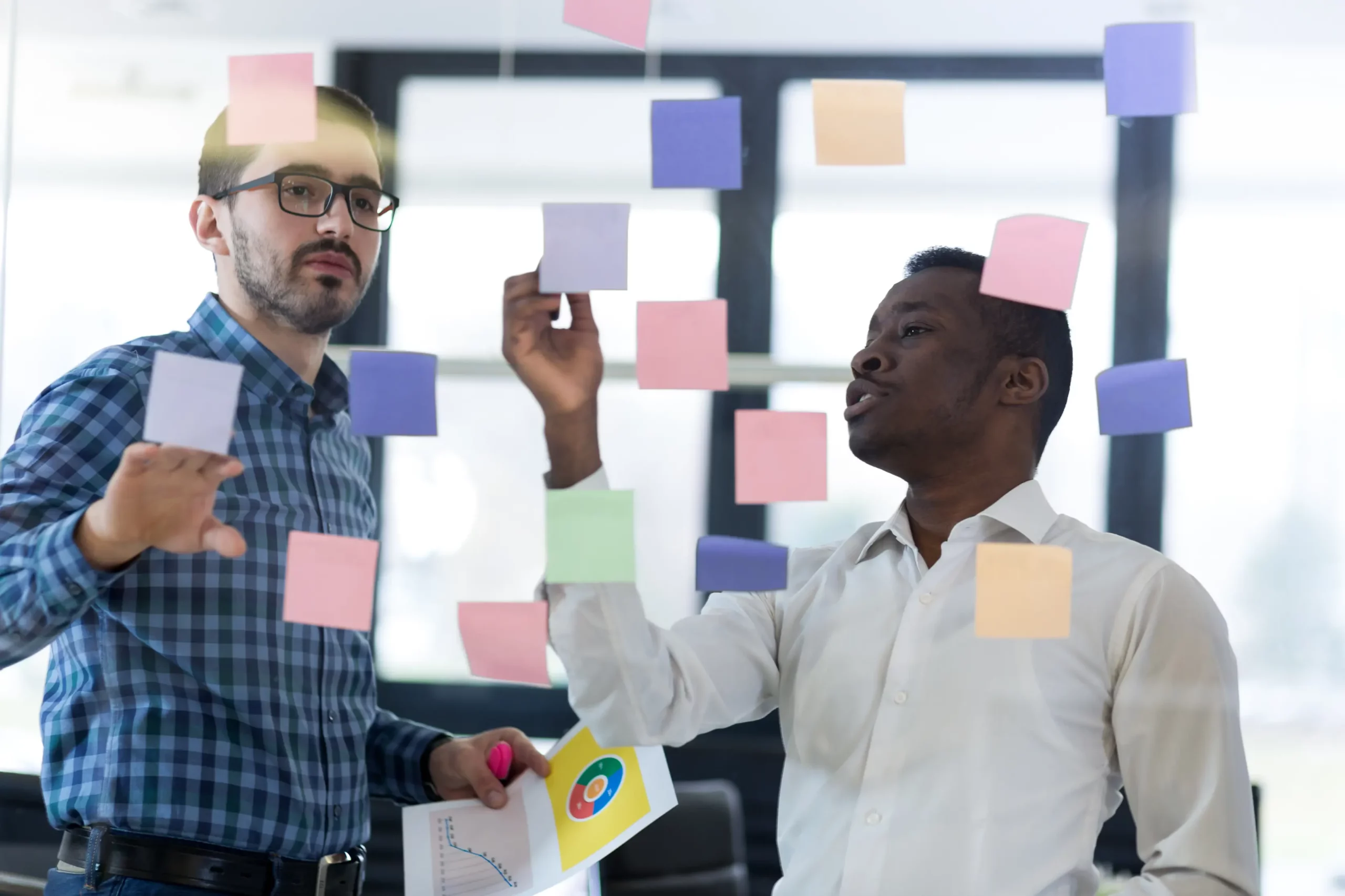 Two men discussing financial data with charts and pie graphs during a business advisory meeting