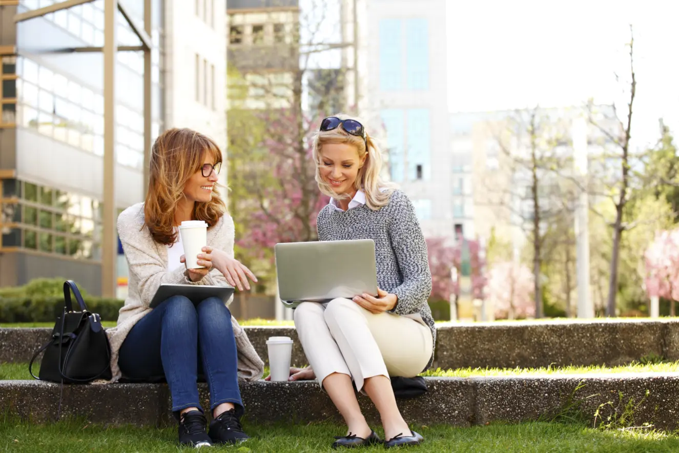 Two women collaborating with a laptop over coffee during a business consulting session