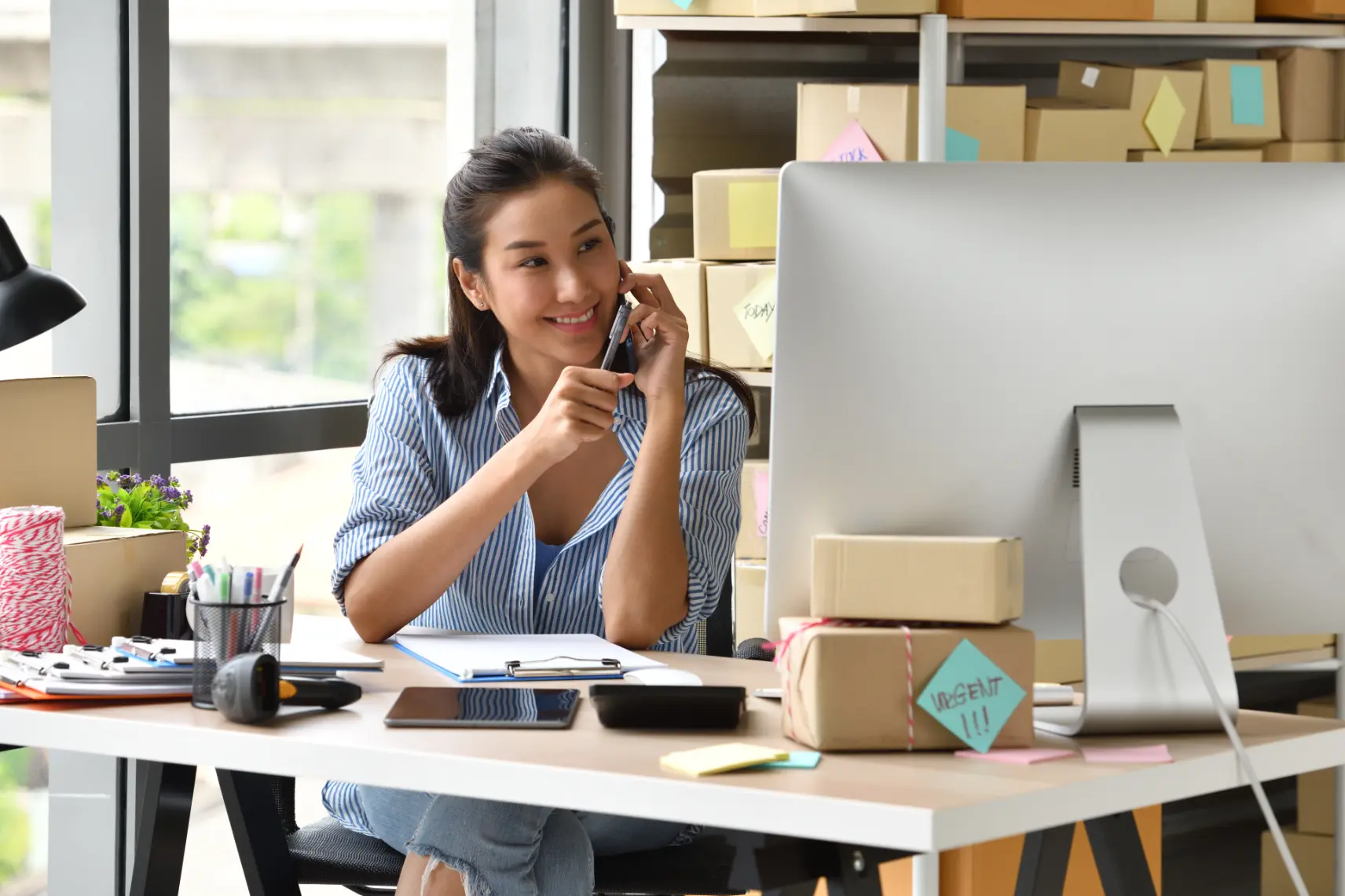 Professional speaking to her phone while reviewing financial data and reports on a desktop